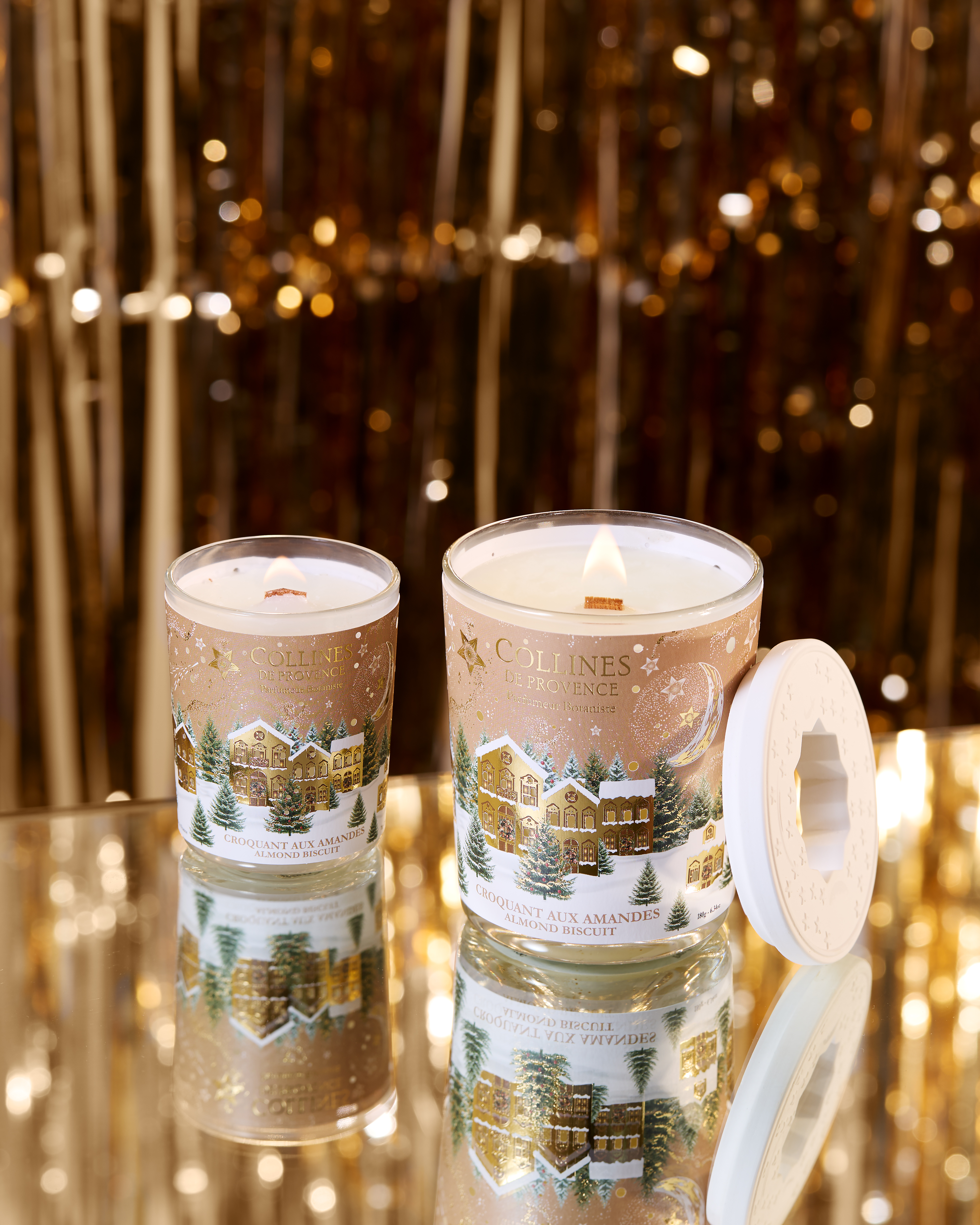 Photo d'une tabl&eacute;e de No&euml;l avec des bougies de diff&eacute;rentes couleurs dispos&eacute;es sur une table festive. Sapin de no&euml;l  en arri&egrave;re plan.