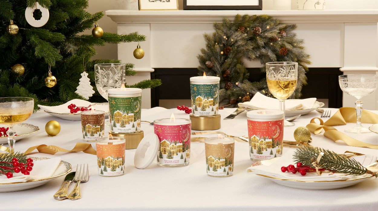 Photo d'une tabl&eacute;e de No&euml;l avec des bougies de diff&eacute;rentes couleurs dispos&eacute;es sur une table festive. Sapin de no&euml;l  en arri&egrave;re plan.