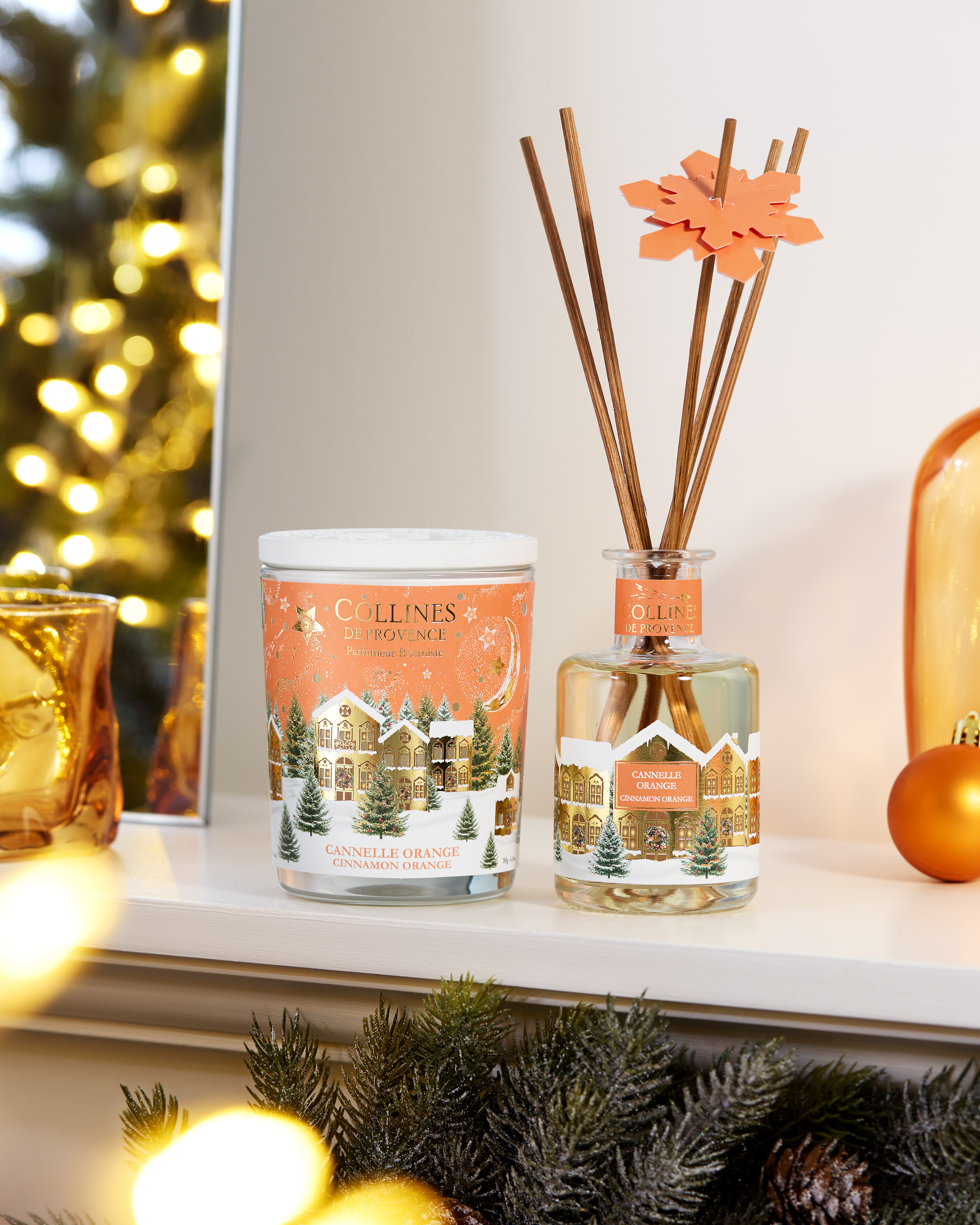 Photo d'une tabl&eacute;e de No&euml;l avec des bougies de diff&eacute;rentes couleurs dispos&eacute;es sur une table festive. Sapin de no&euml;l  en arri&egrave;re plan.