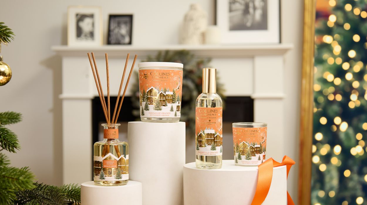 Photo d'une tabl&eacute;e de No&euml;l avec des bougies de diff&eacute;rentes couleurs dispos&eacute;es sur une table festive. Sapin de no&euml;l  en arri&egrave;re plan.