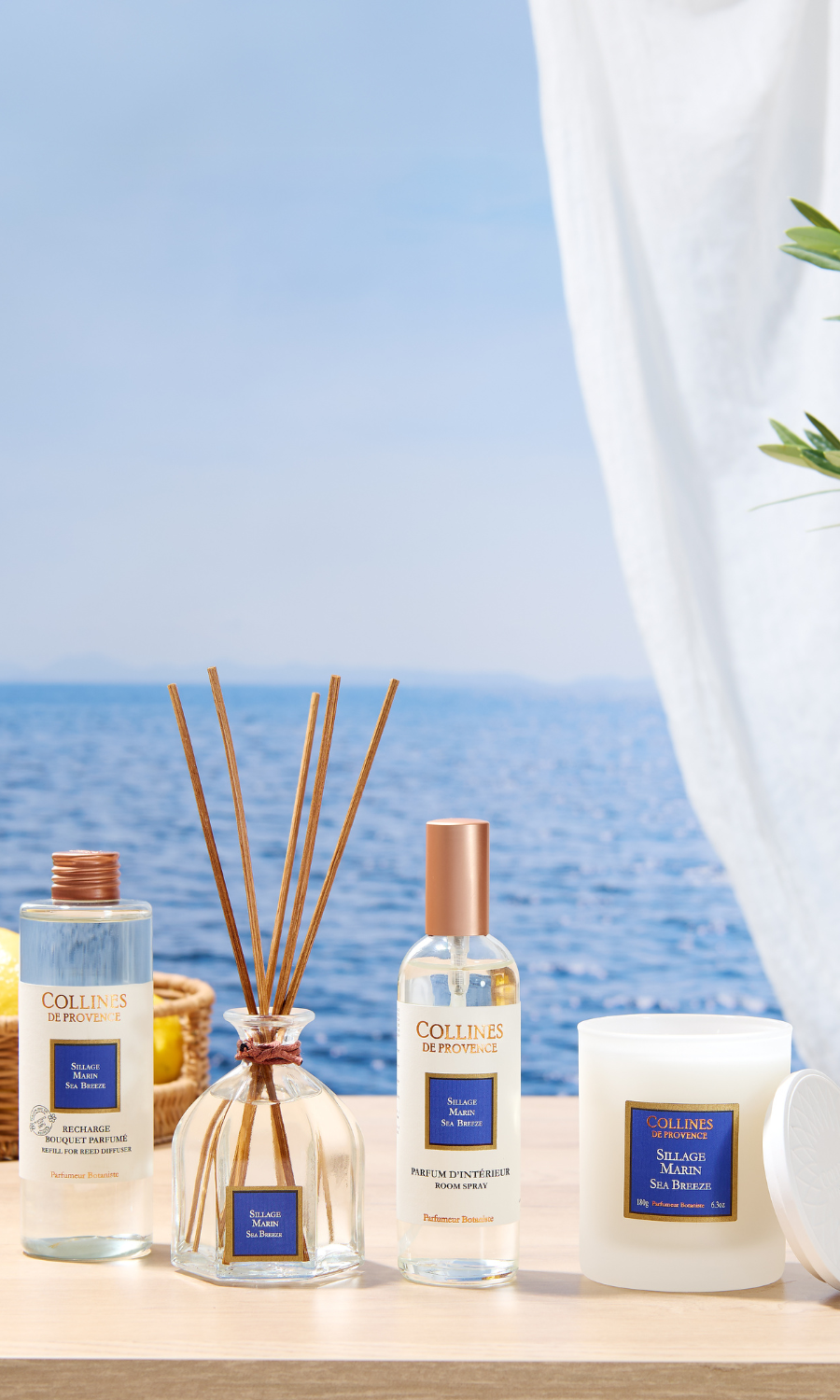 Diffuseur et recharge parfum Coquelicot Collines de Provence, entour&eacute;s de fleurs rouges sur fond de ciel bleu.